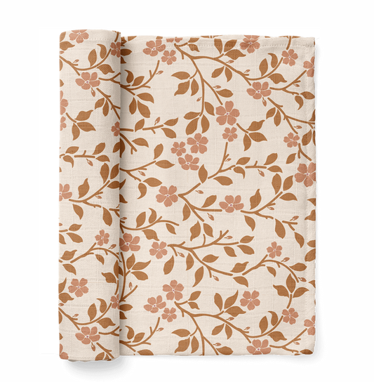 half rolled magnolia tree swaddle blanket in brown color showcasing the rounded petals and leaves of the magnolia tree