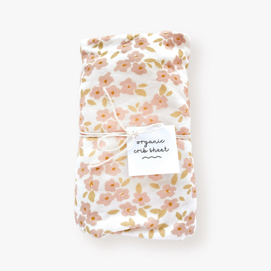 Organic cotton jersey crib sheet with small hand-drawn peachy pink flowers on a white back dropdard crib mattresses. 