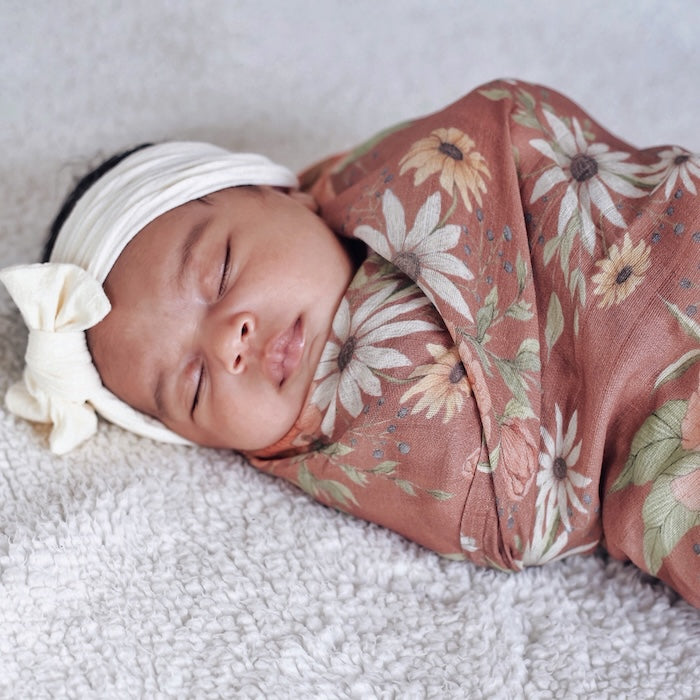 little baby sleeping in her boho nursery comfortably snuggled in her spring blossom clay muslin baby swaddles