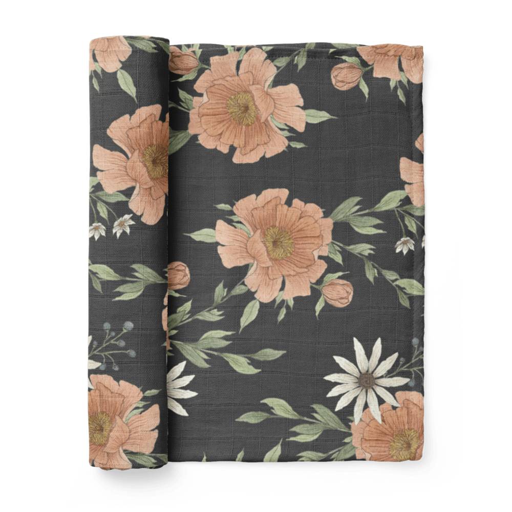 peony bloom swaddle blanket. pretty illustrations of a pink peony flower on a dark charcoal gray backdrop. The cotton blanket is rolled up.