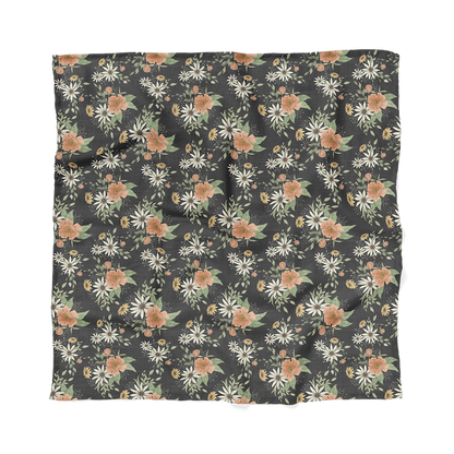 a photo of our spring blossom charcoal gray cotton swaddle laid flat showing the entire print of daisies, peonies and more