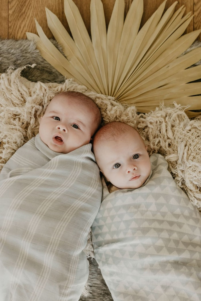 cute babies wrapped in high quality cotton muslin fabric stripe baby swaddle and triangle baby swaddle looking innocently at the camera