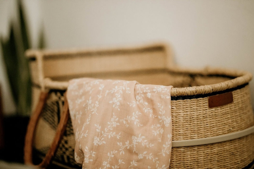 a peach blanket for baby hanging on the baby bassinet showing the bloom peach patterns