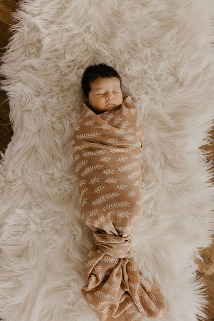 a swaddled baby sleeping soundly in our swaddling blankets on top of a white faux fur background