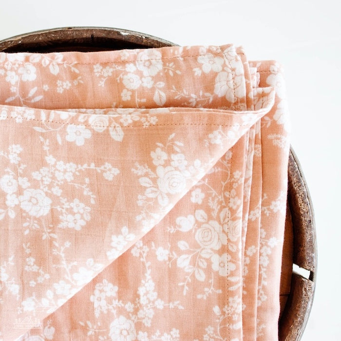 a close up photo of the folded vintage bouquet swaddle blanket in the color peach