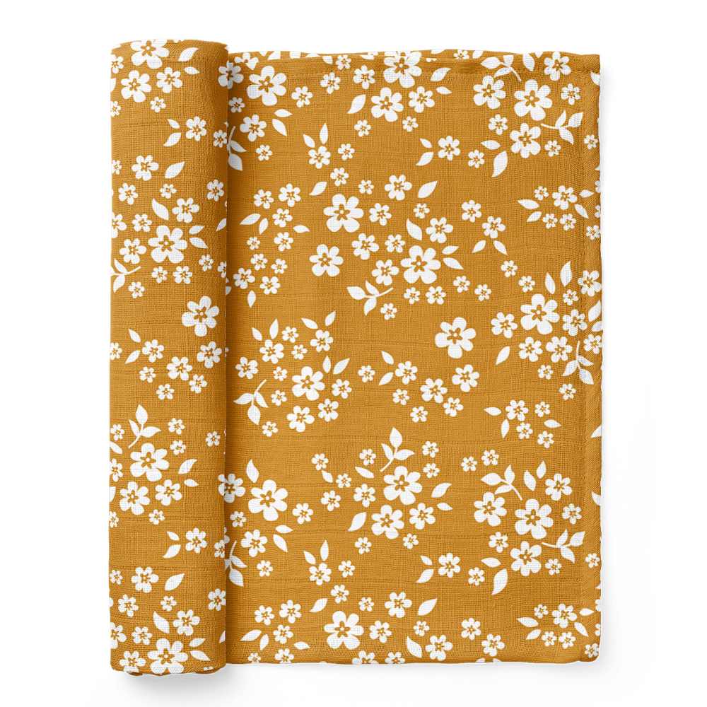 A half-rolled Mini Wander swaddle with a rich, yellow, and whimsical Floral design.