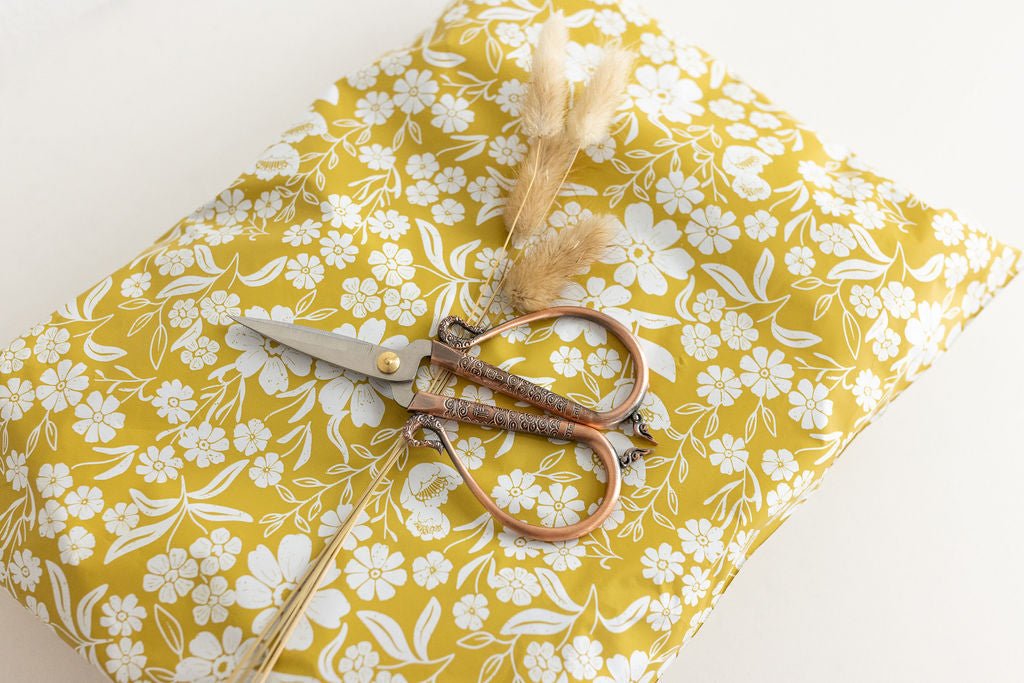 yellow 6x9 polymailer shipping bag with a rustic floral arrangement on top as well as a rustic scissors laid on top of the yellow mailers