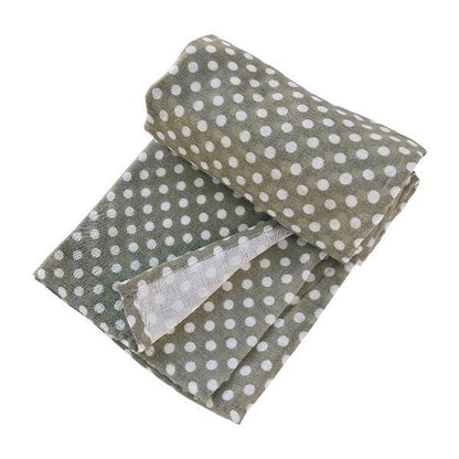 sage green polka dot swaddle blanket in a half rolled and halfway wrapped angle