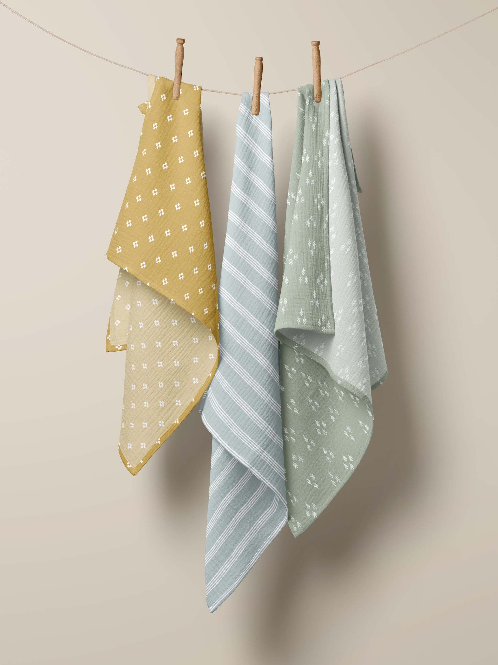 Three swaddles comprising the baby gift set for boy hanging in clothesline with clothespin 