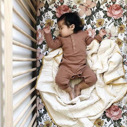 cute little baby wearing a boho baby clothes sleeping cozily in her vintage floral crib sheet 