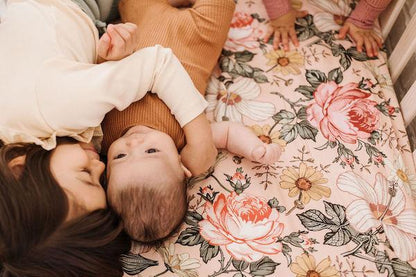 priceless sibling moments enjoying their pink crib sheets with the big sister hugging her baby sister wearing brown boho baby clothes that perfectly matches their favorite nursery decor baby crib sheets