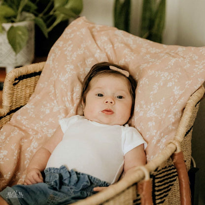 a sweet girl lounging on her peach summer blanket while looking blankly at the camera 